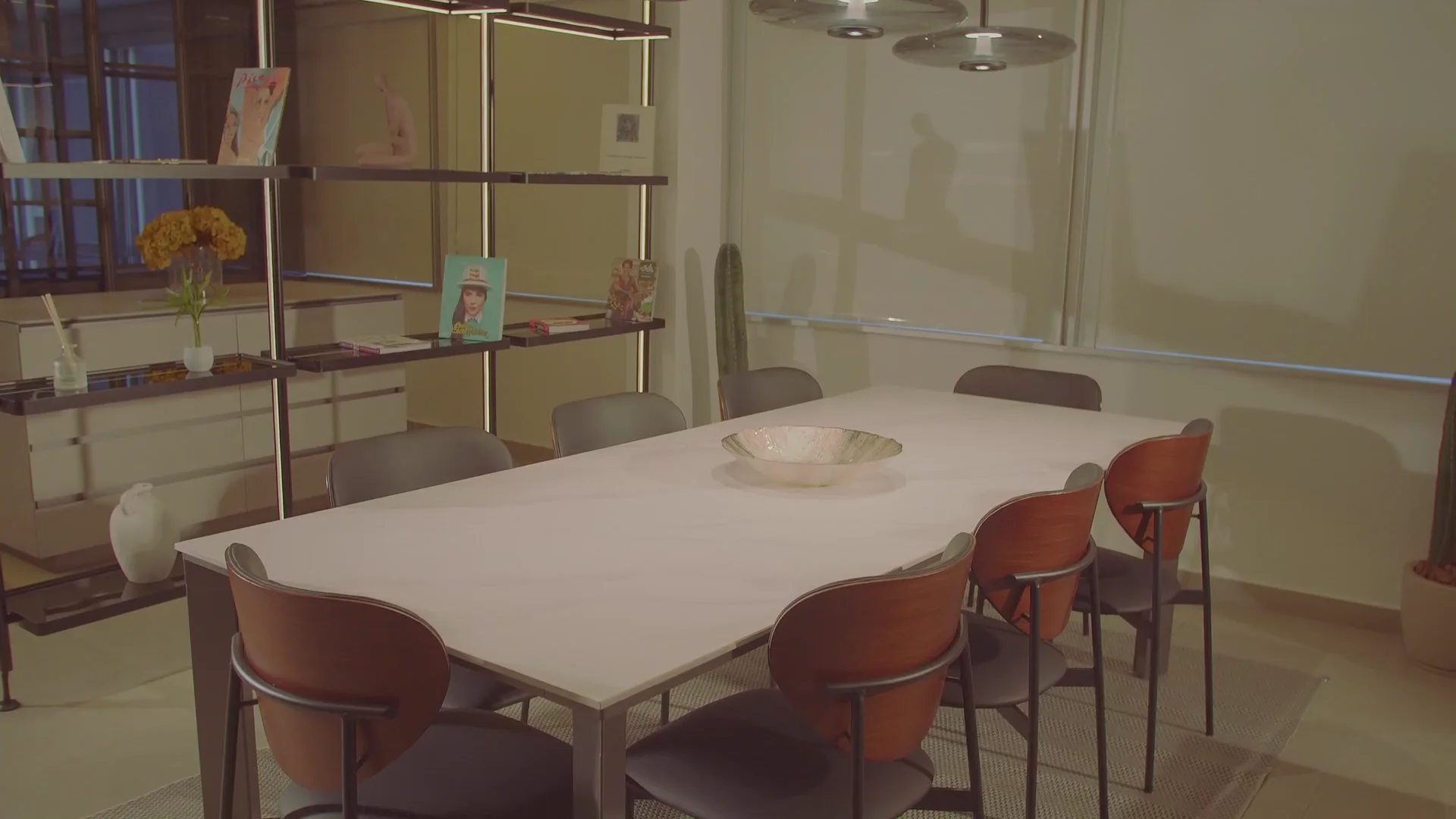 Sala de jantar do ateliê com mesa de pedra e estante iluminada